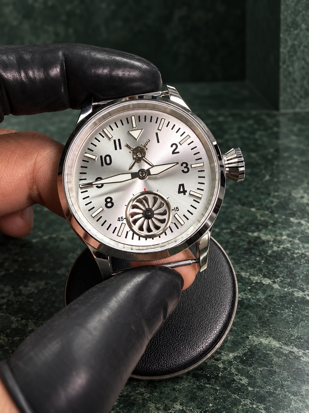 A finished silver watch in gloved hands